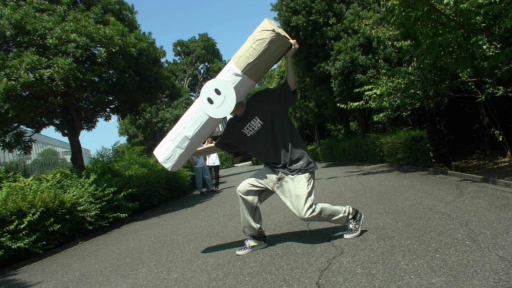 屋外で大きな小道具を掲げる様子